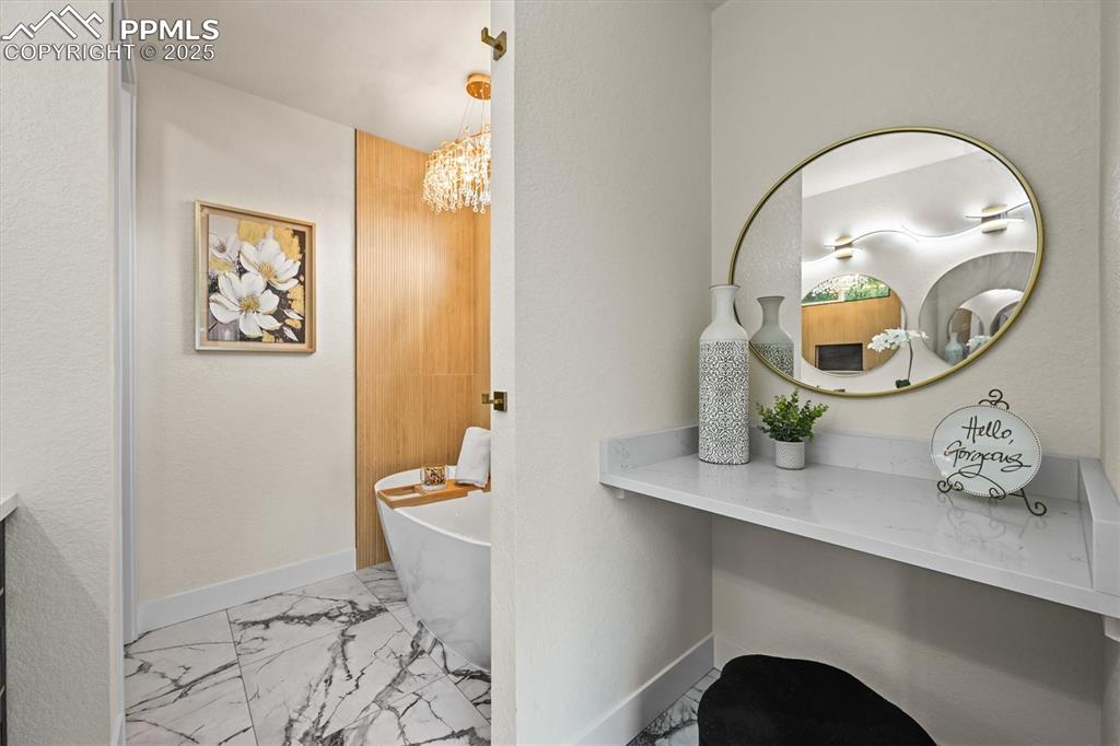 Image 36 of 47: Full bath featuring a freestanding bath, light marble finish flooring, vani