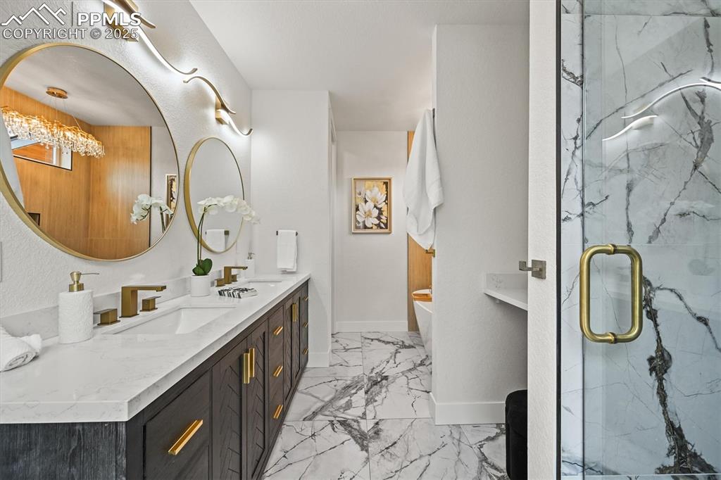 Image 37 of 47: Bathroom with double vanity, a soaking tub, a marble finish shower, and lig