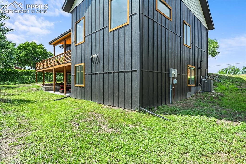 Image 46 of 47: View of side of home featuring board and batten siding, a patio, and a yard