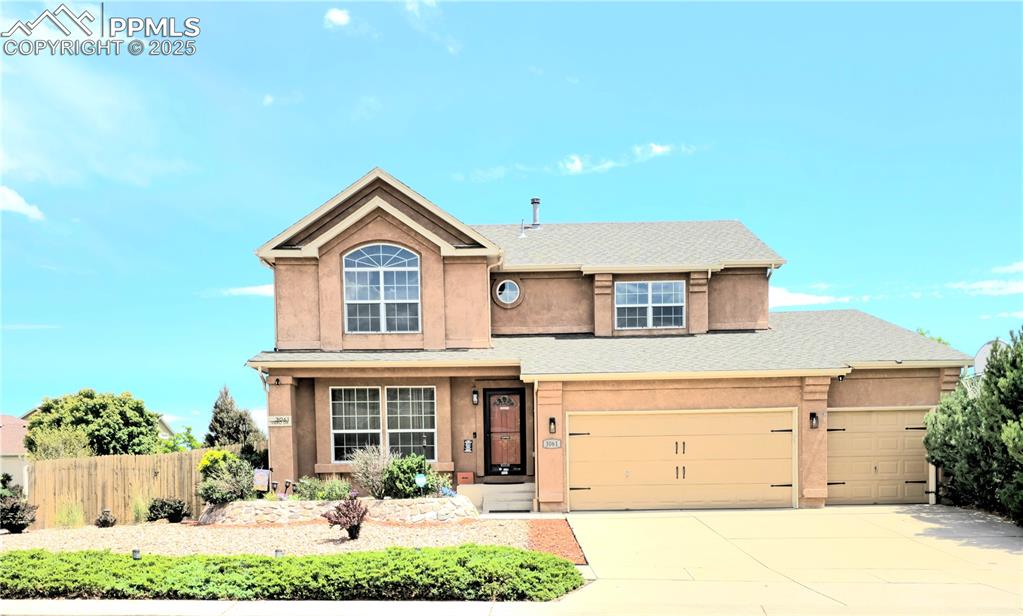 Caption: Traditional-style house with stucco siding, driveway, a shingled roof, and a garage