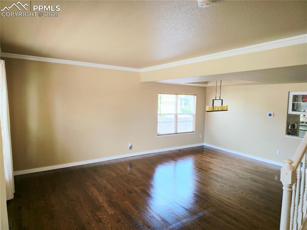 Image 2 of 48: Spare room with dark wood-style floors, ornamental molding, and a textured