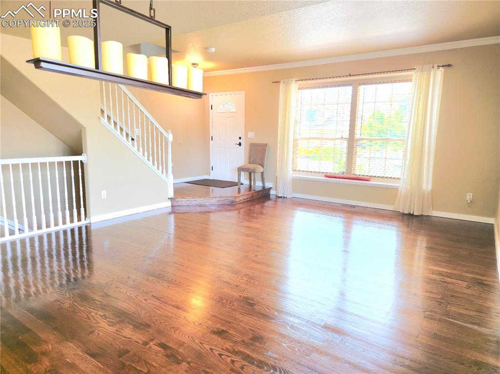 Image 4 of 48: Entrance foyer with dark wood-style flooring, crown molding, and stairs
