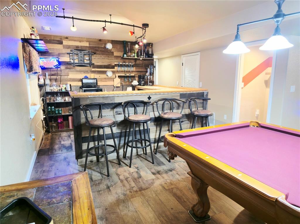 Image 42 of 48: basement Rec room with wood-type flooring, bar area, a textured ceiling, an
