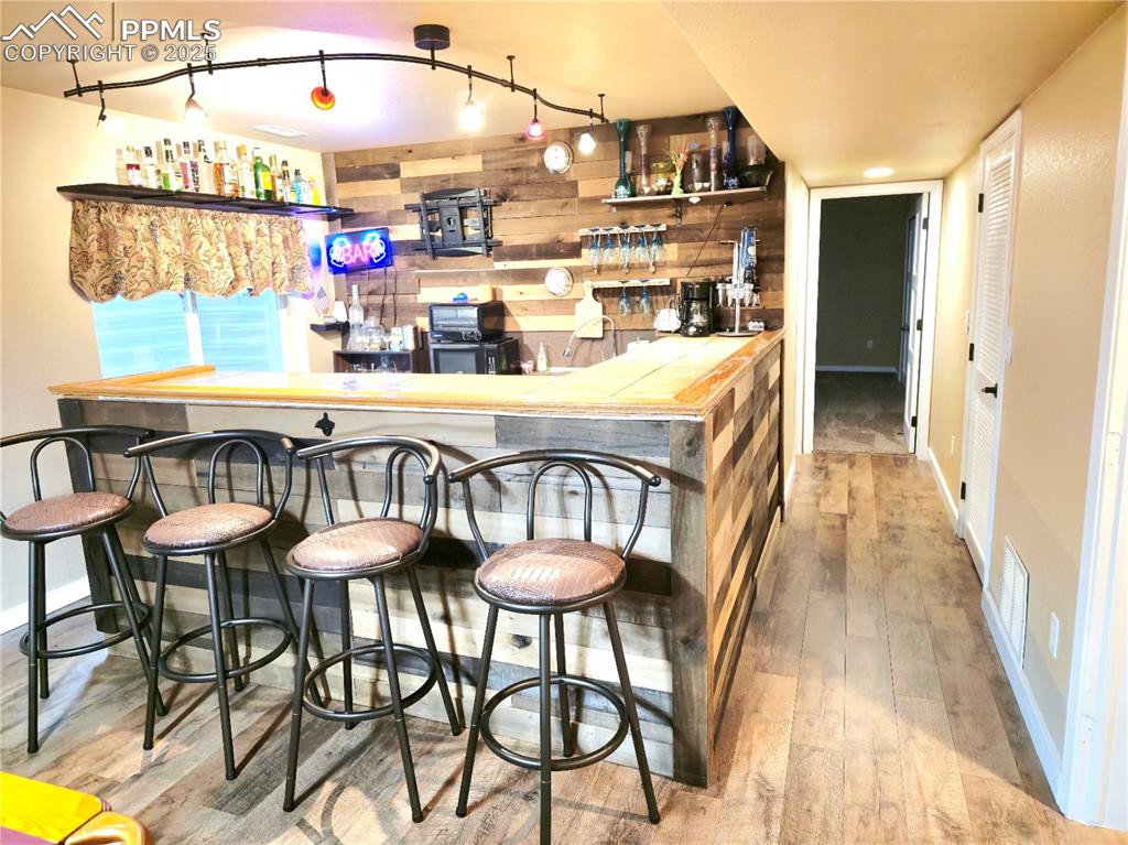 Image 43 of 48: basement Rec room with wood finished floors, a dry bar, wooden walls, and p