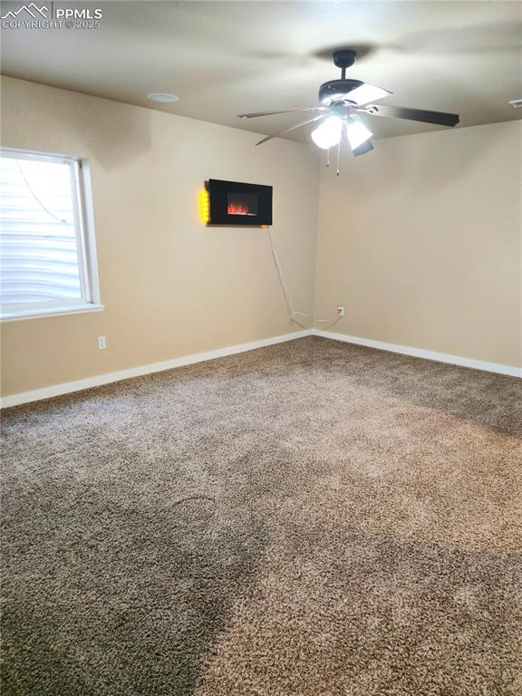 Image 46 of 48: Easement bedroom5 with a ceiling fan, a glass covered fireplace, dark carpe