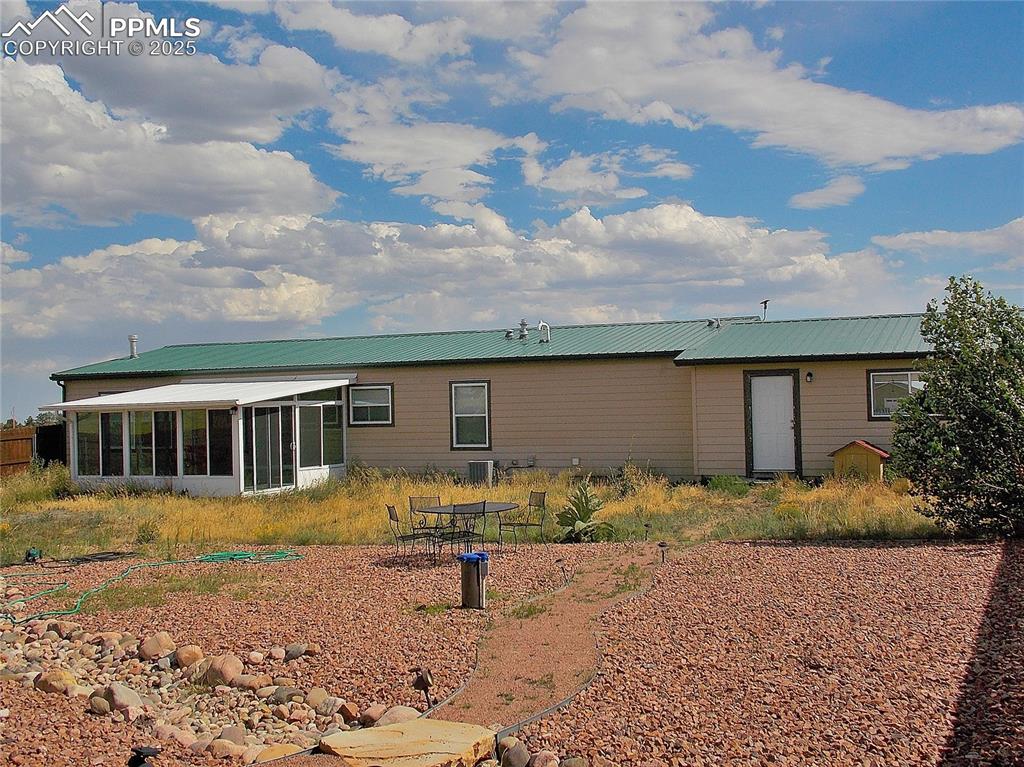 Image 19 of 33: Back of house featuring a sunroom and door to garage