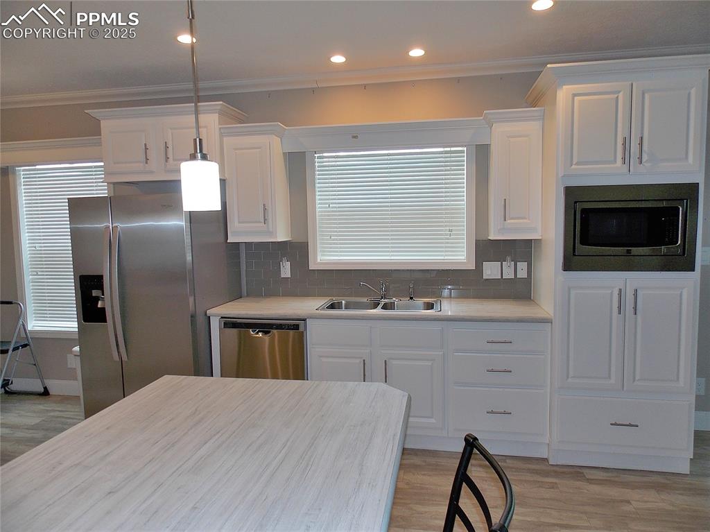 Image 8 of 33: Kitchen with white cabinetry, tasteful backsplash, appliances with stainles