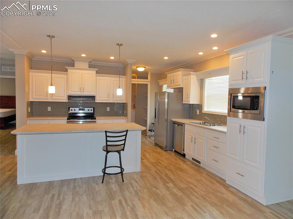 Image 9 of 33: Kitchen with appliances with stainless steel finishes, white cabinets, ligh