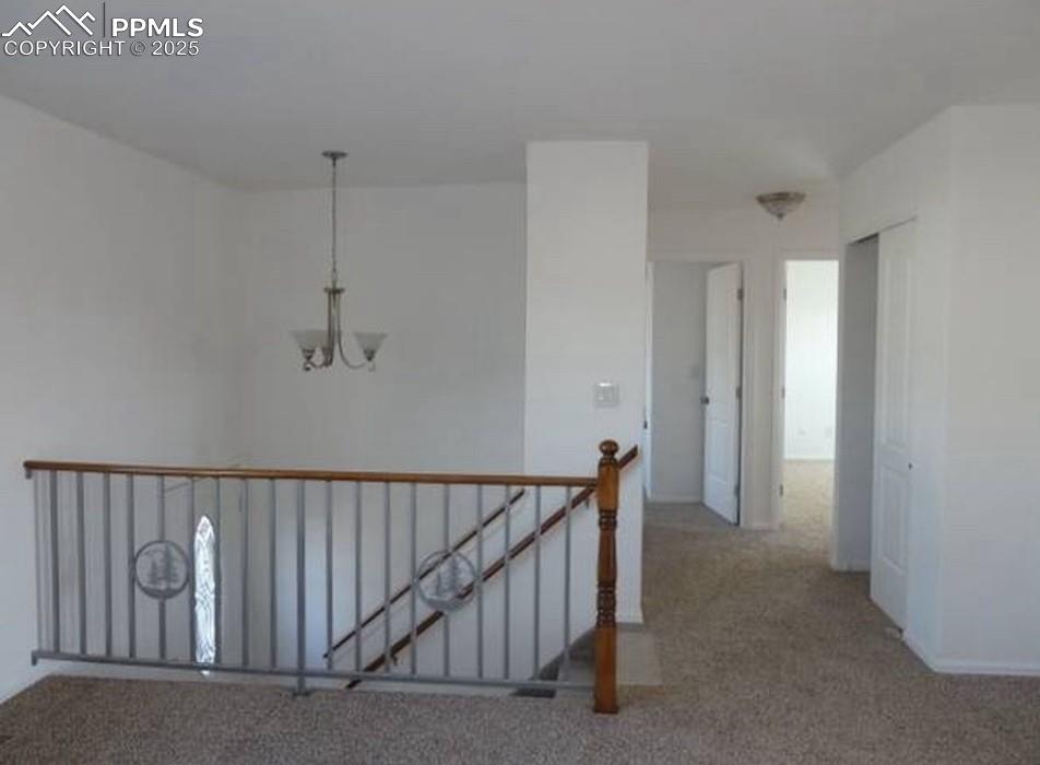 Image 3 of 8: Corridor with a chandelier, carpet floors, and an upstairs landing