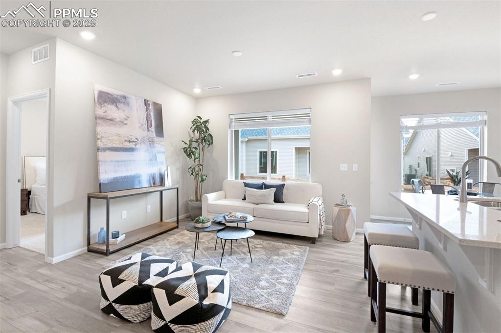 Image 13 of 28: Living area with light wood-style floors and recessed lighting