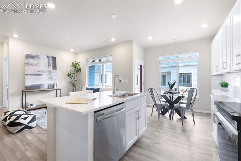 Image 16 of 28: Kitchen with white cabinets, light stone counters, stainless steel applianc