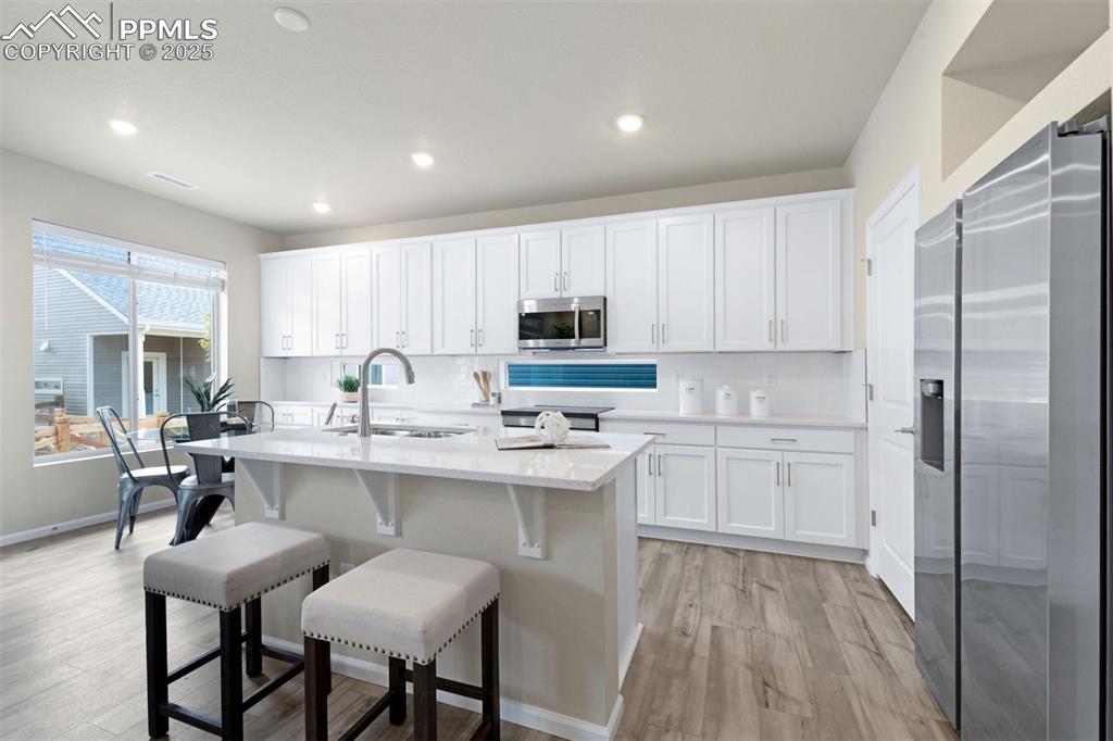 Image 17 of 28: Kitchen with stainless steel appliances, white cabinetry, a kitchen island 