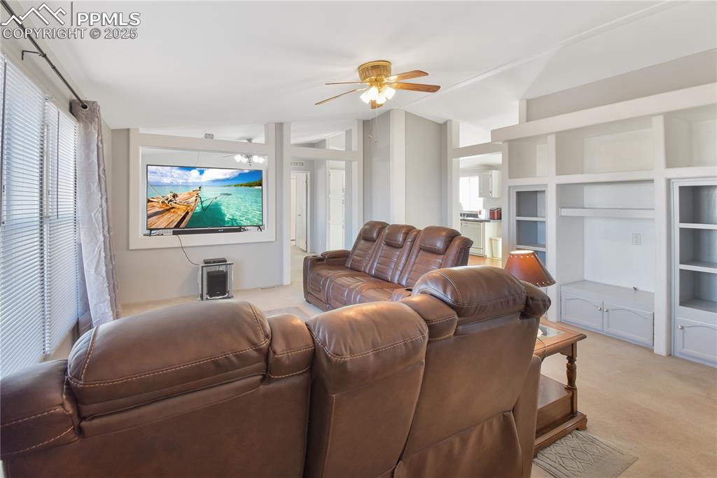 Image 10 of 34: Living area with lofted ceiling, ceiling fan, and light colored carpet
