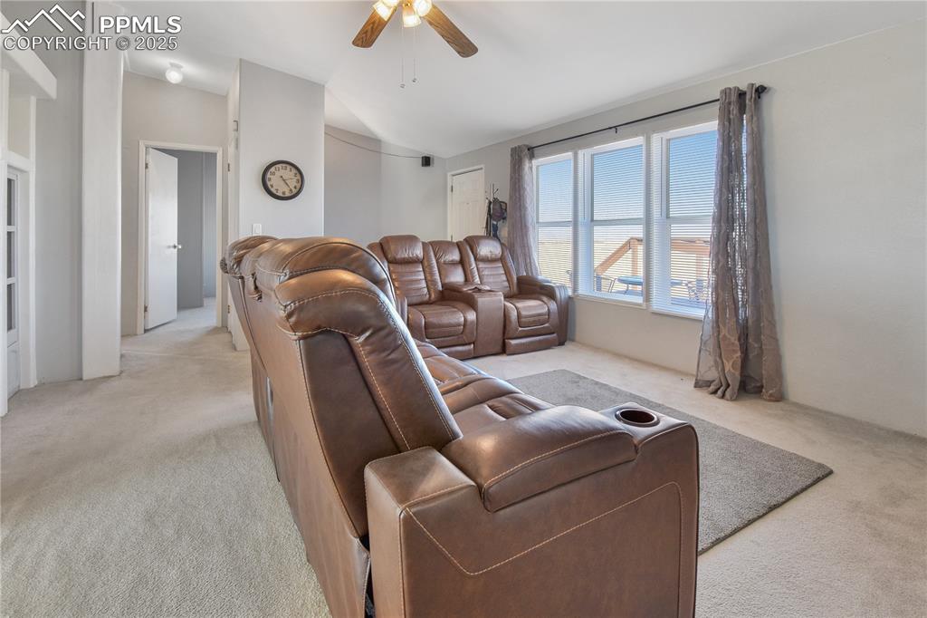 Image 11 of 34: Living room with light carpet, vaulted ceiling, and a ceiling fan