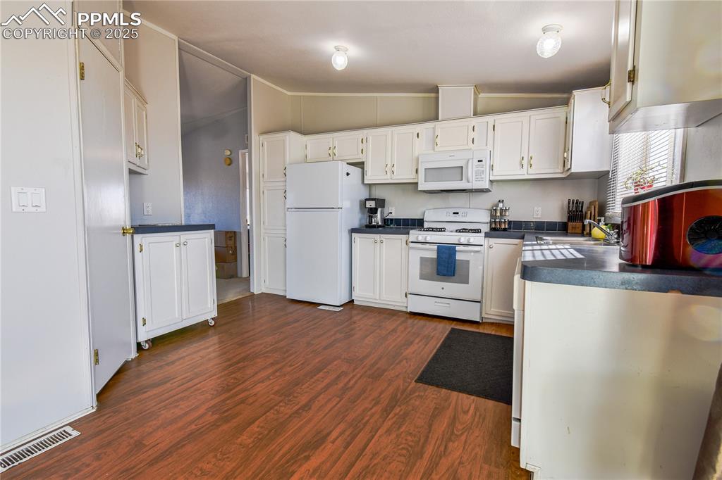 Image 13 of 34: Kitchen featuring dark countertops, dark wood finished floors, white applia
