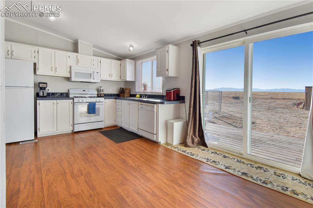 Image 15 of 34: Kitchen featuring dark countertops, white appliances, light wood-type floor