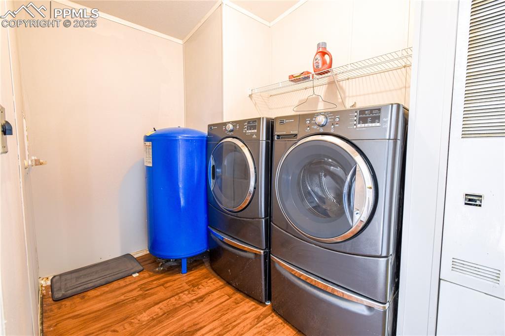Image 16 of 34: Laundry area with a heating unit, wood finished floors, washing machine and