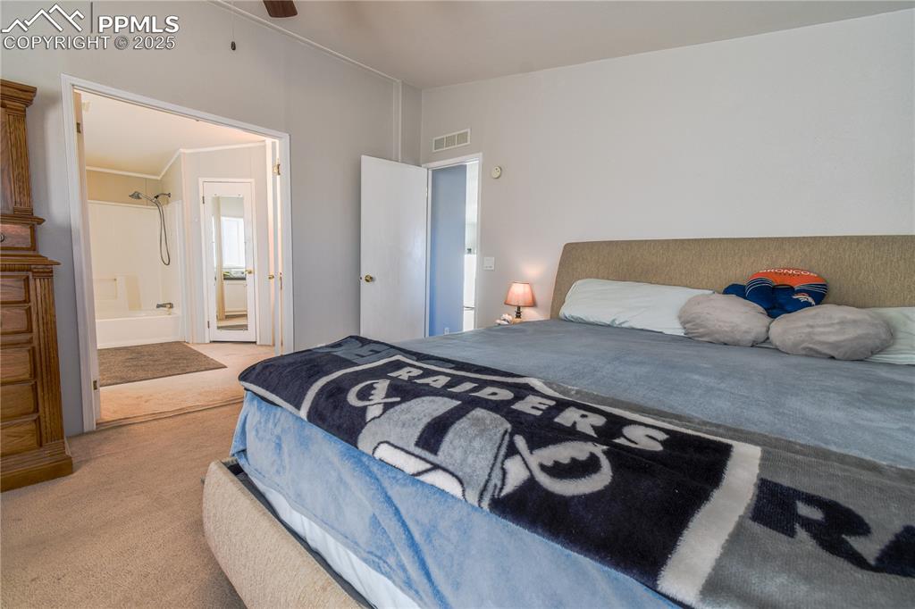 Image 26 of 34: Carpeted bedroom featuring ensuite bath, vaulted ceiling, and a ceiling fan