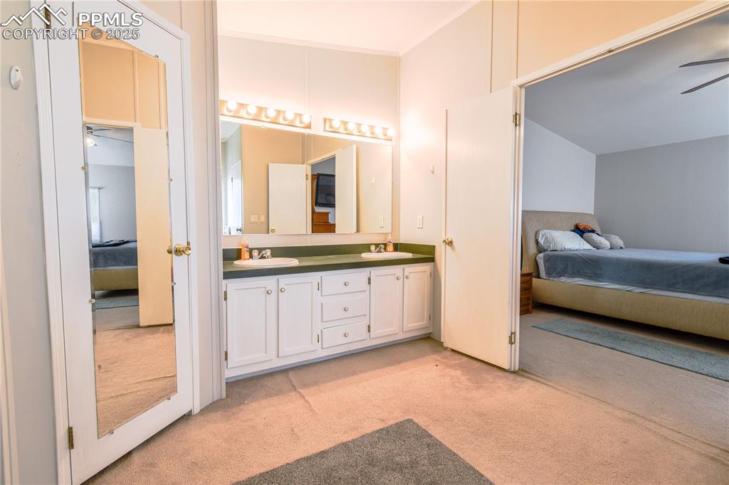 Image 28 of 34: Full bath with connected bathroom, ceiling fan, light colored carpet, and d