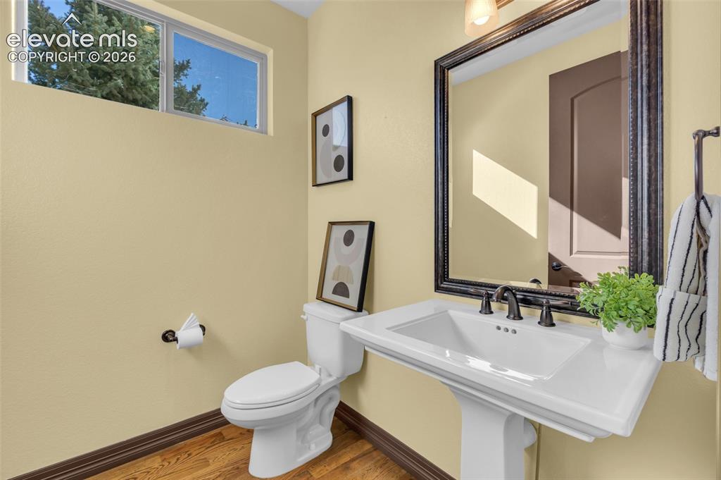 Image 22 of 50: Powder room featuring wood-finish flooring, a white porcelain pedestal sink