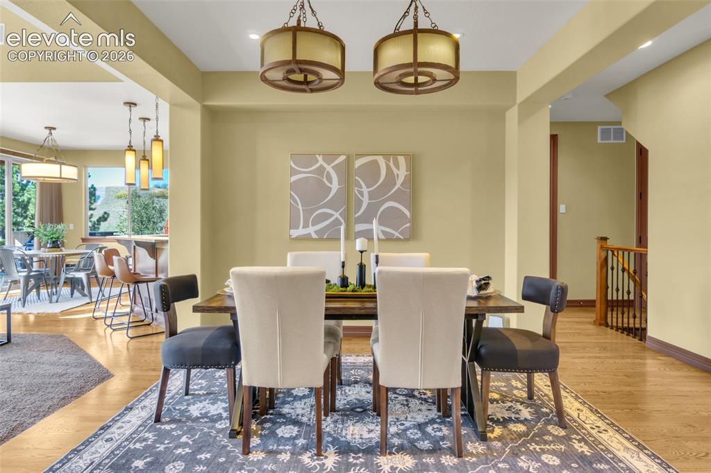 Image 23 of 50: Dining area featuring dual drum-style pendant lights, wood-finish flooring,