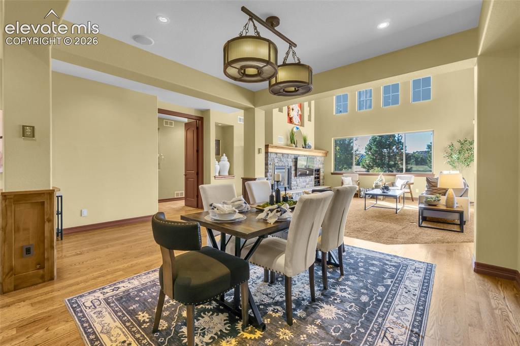 Image 24 of 50: Open-concept space featuring wood-finish flooring, stone-surround fireplace