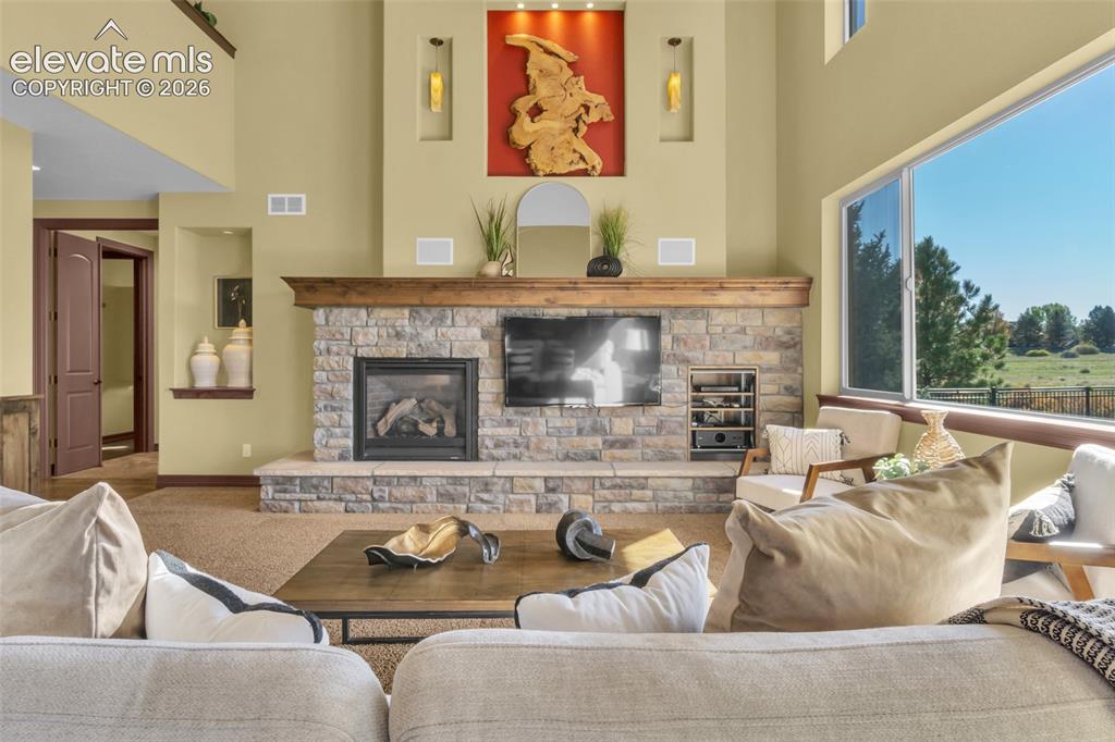 Image 26 of 50: Floor-to-ceiling stone fireplace with a prominent timber mantel, vaulted ce