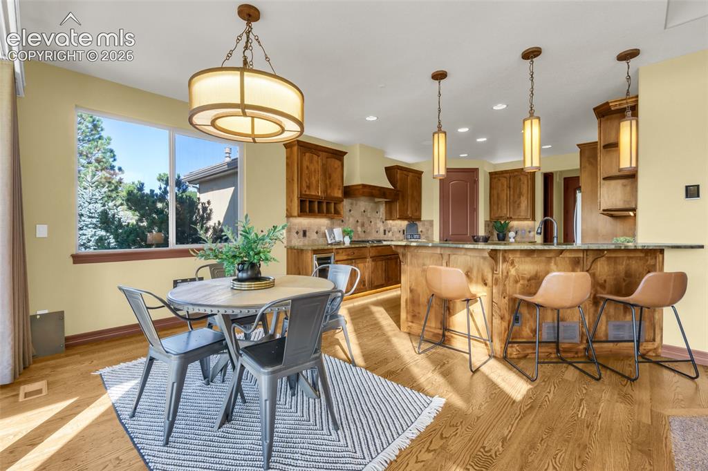 Image 31 of 50: Open-concept kitchen and dining area featuring custom wood cabinetry, stain