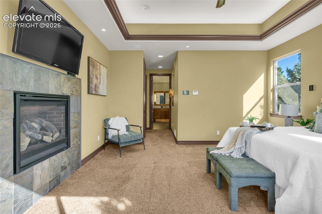 Image 34 of 50: Tray ceiling with crown molding, stone-surround fireplace, recessed lightin