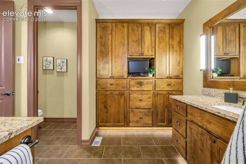 Image 36 of 50: Custom built-in wood cabinetry, stone-finish countertops, tiled flooring, w