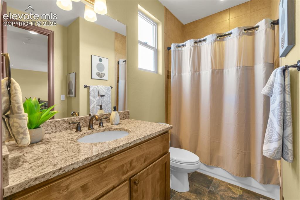 Image 41 of 50: Bathroom featuring a wood vanity with a stone-finish countertop, undermount