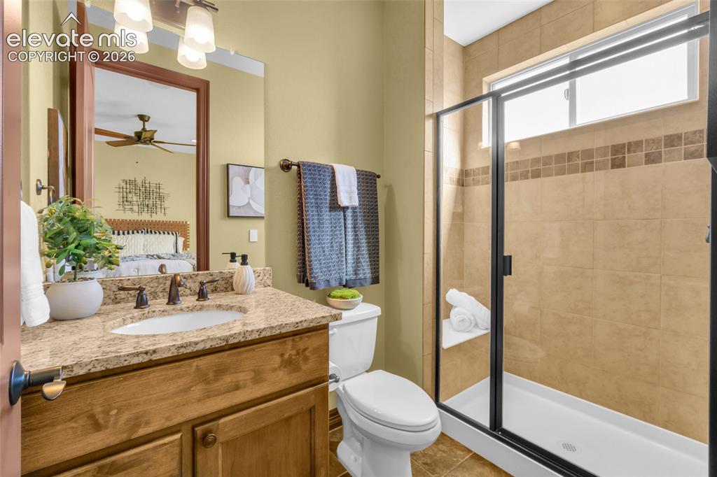 Image 45 of 50: Bathroom featuring a wood-finish vanity with a stone-composite countertop, 
