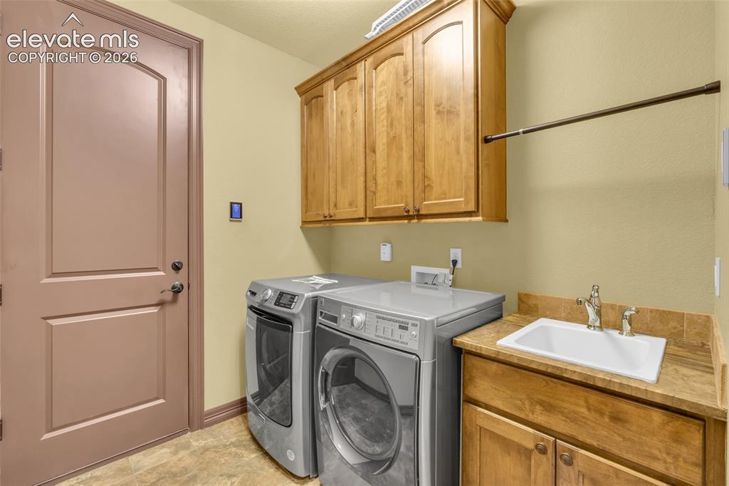 Image 46 of 50: Utility area featuring wood-finish cabinetry, a drop-in sink with a high-ar