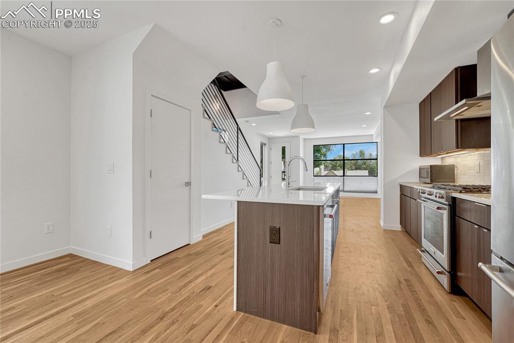 Image 11 of 49: Kitchen with stainless steel range with gas cooktop, modern cabinets, light