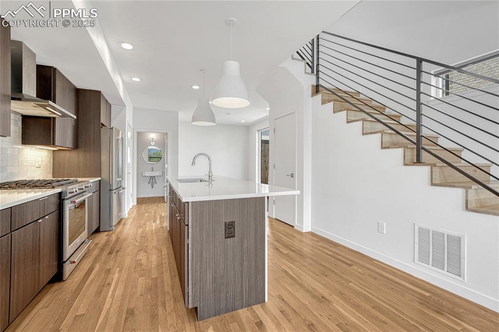 Image 12 of 49: Kitchen featuring high quality appliances, wall chimney range hood, modern