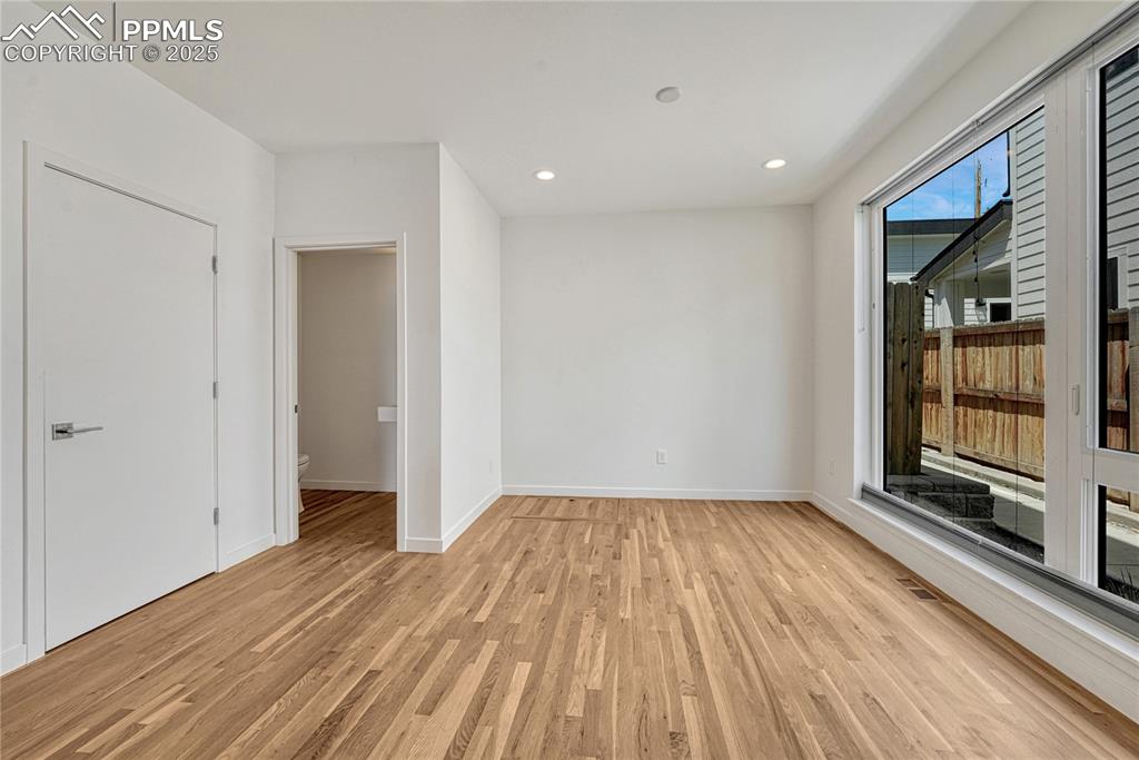 Image 16 of 49: Empty room with light wood-style floors and recessed lighting