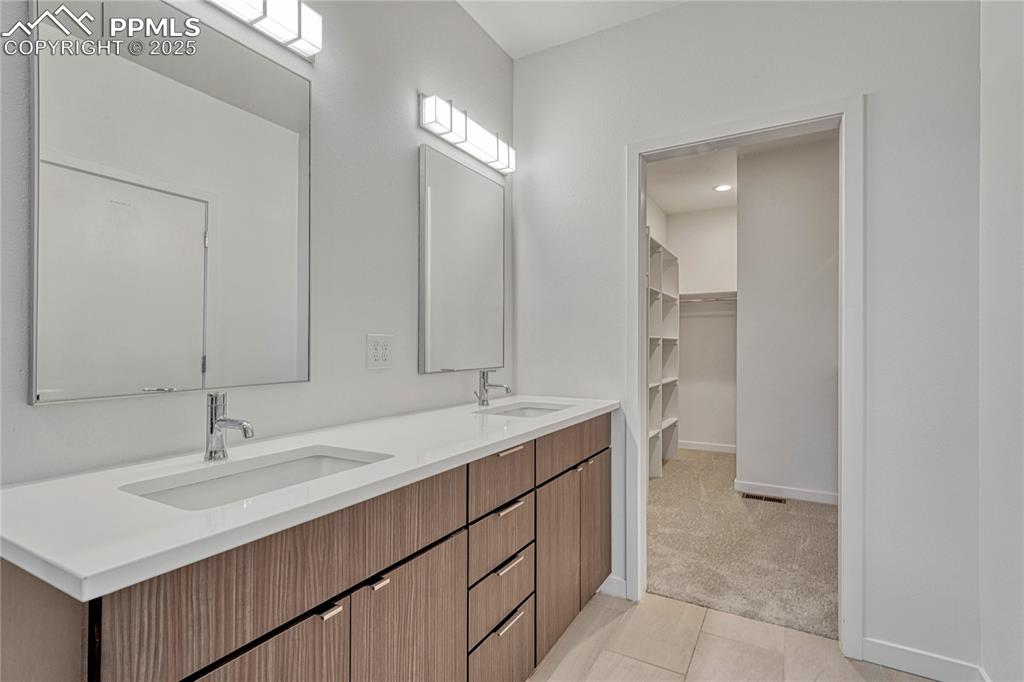 Image 24 of 49: Full bath with double vanity, tile patterned flooring, and a spacious close