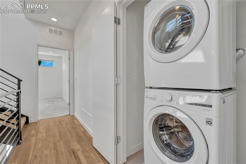 Image 31 of 49: Washroom with stacked washer / dryer, light wood finished floors, and reces