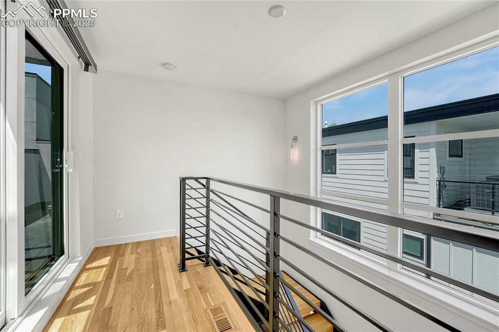 Image 34 of 49: Hallway with light wood-style floors and an upstairs landing
