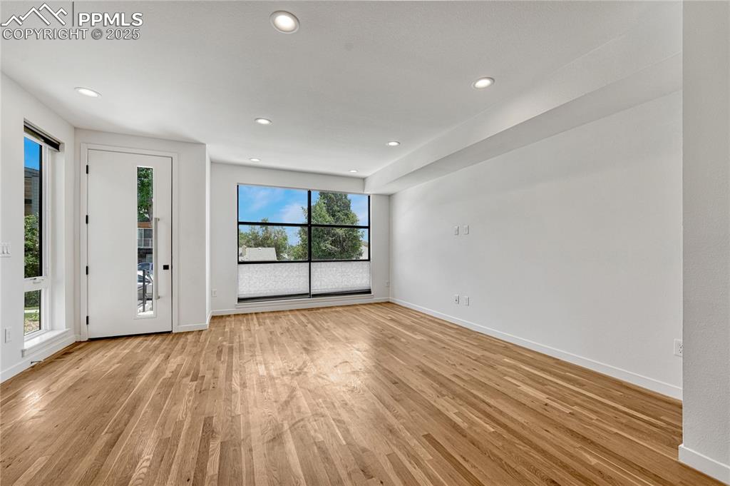 Image 4 of 49: Empty room with light wood-style floors and recessed lighting