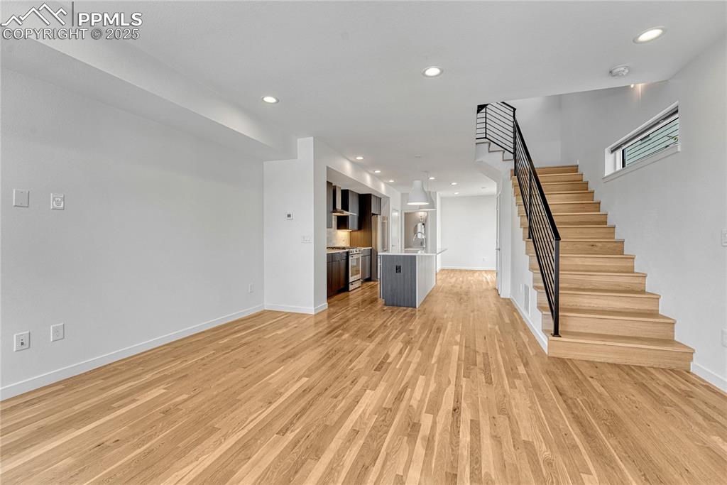 Image 7 of 49: Unfurnished living room with stairs, light wood finished floors, and recess