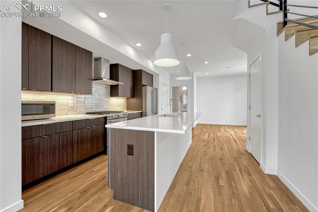 Image 8 of 49: Kitchen featuring wall chimney exhaust hood, appliances with stainless stee