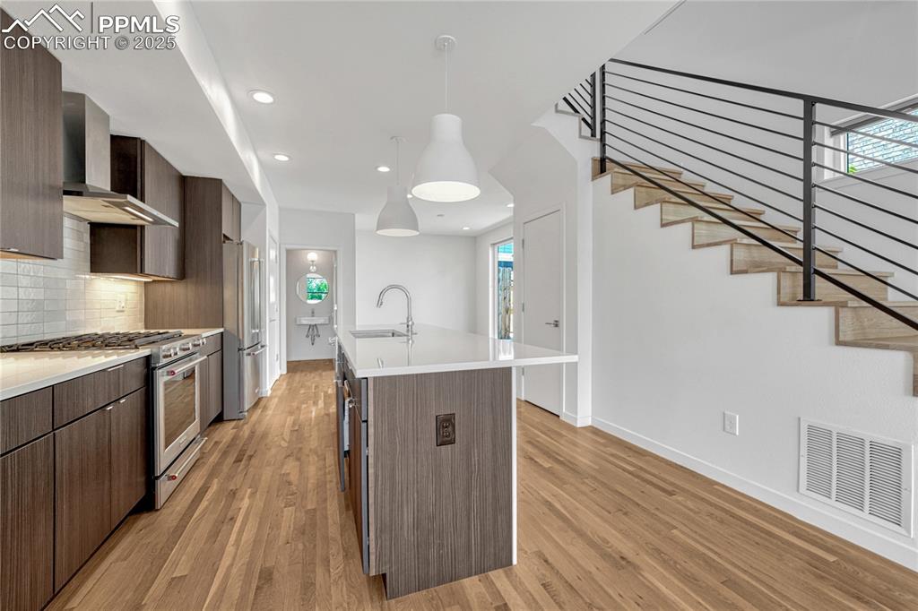 Image 9 of 49: Kitchen with high end appliances, wall chimney exhaust hood, modern cabinet