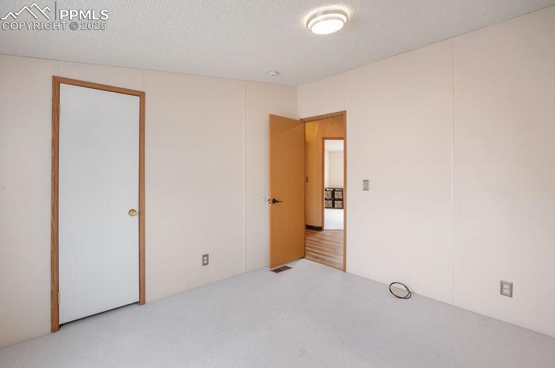 Image 24 of 32: Unfurnished bedroom featuring visible vents, carpet, and a textured ceiling