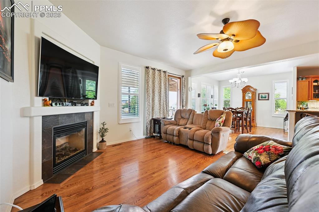 Image 17 of 45: Living room featuring light wood-type flooring, a fireplace, a ceiling fan,
