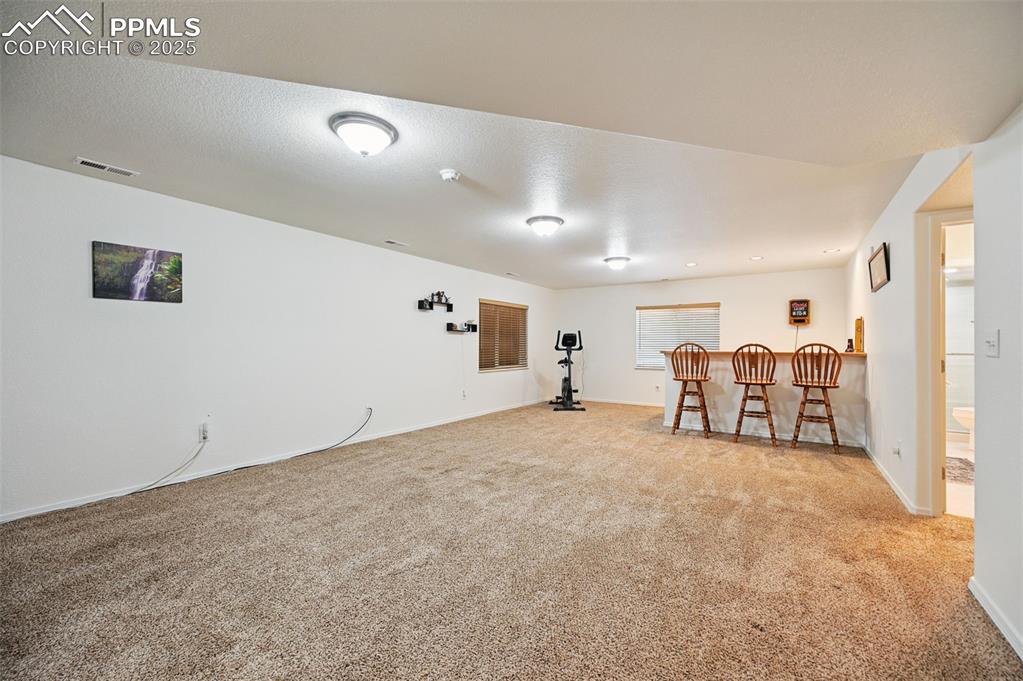 Image 30 of 45: Sitting room featuring carpet, a textured ceiling, and a dry bar