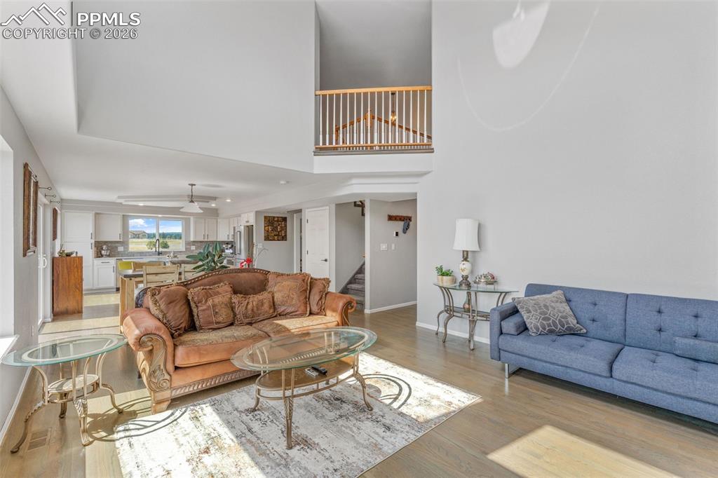 Image 11 of 47: Living area with wood finished floors, a high ceiling, and a ceiling fan