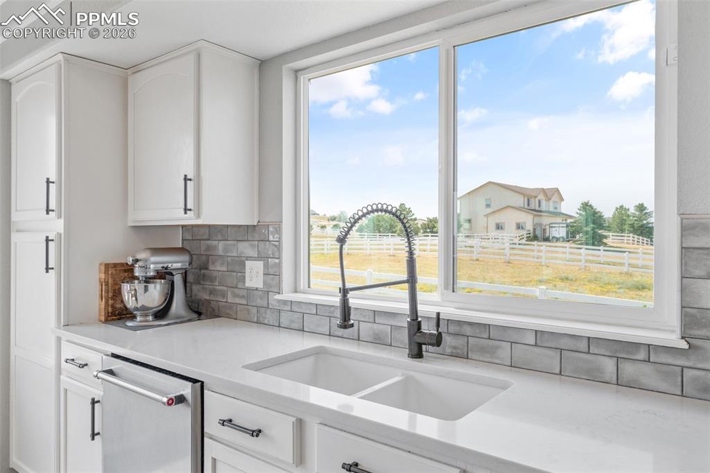 Image 16 of 47: Kitchen featuring white cabinets, light stone countertops, stainless steel 