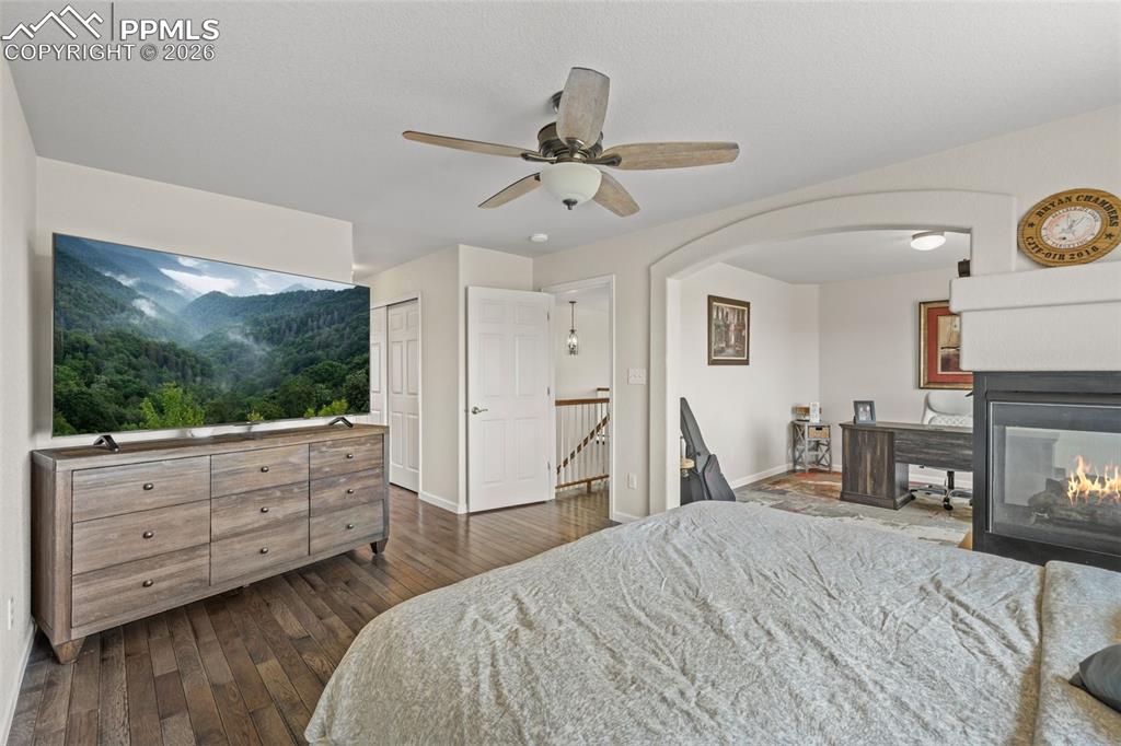 Image 22 of 47: Bedroom with dark wood-style flooring, a ceiling fan, arched walkways, and 