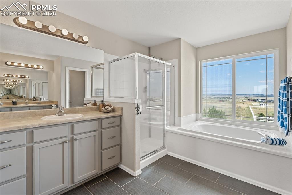 Image 24 of 47: Full bath featuring a bath, a stall shower, and vanity